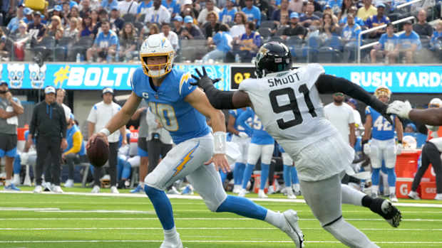 Sep 25, 2022; Inglewood, California, USA; Los Angeles Chargers quarterback Justin Herbert (10) runs the ball under pressure from Jacksonville Jaguars defensive end Dawuane Smoot (91) in the third quarter at SoFi Stadium. Mandatory Credit: Kirby Lee-USA TODAY Sports